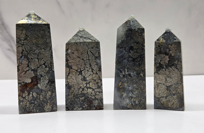 Four dark stone obelisks on a white surface with a gray background