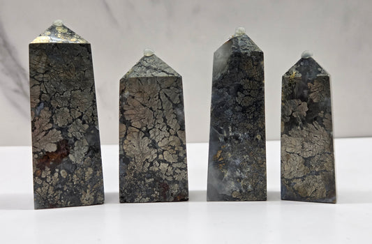 Four dark stone obelisks on a white surface with a gray background