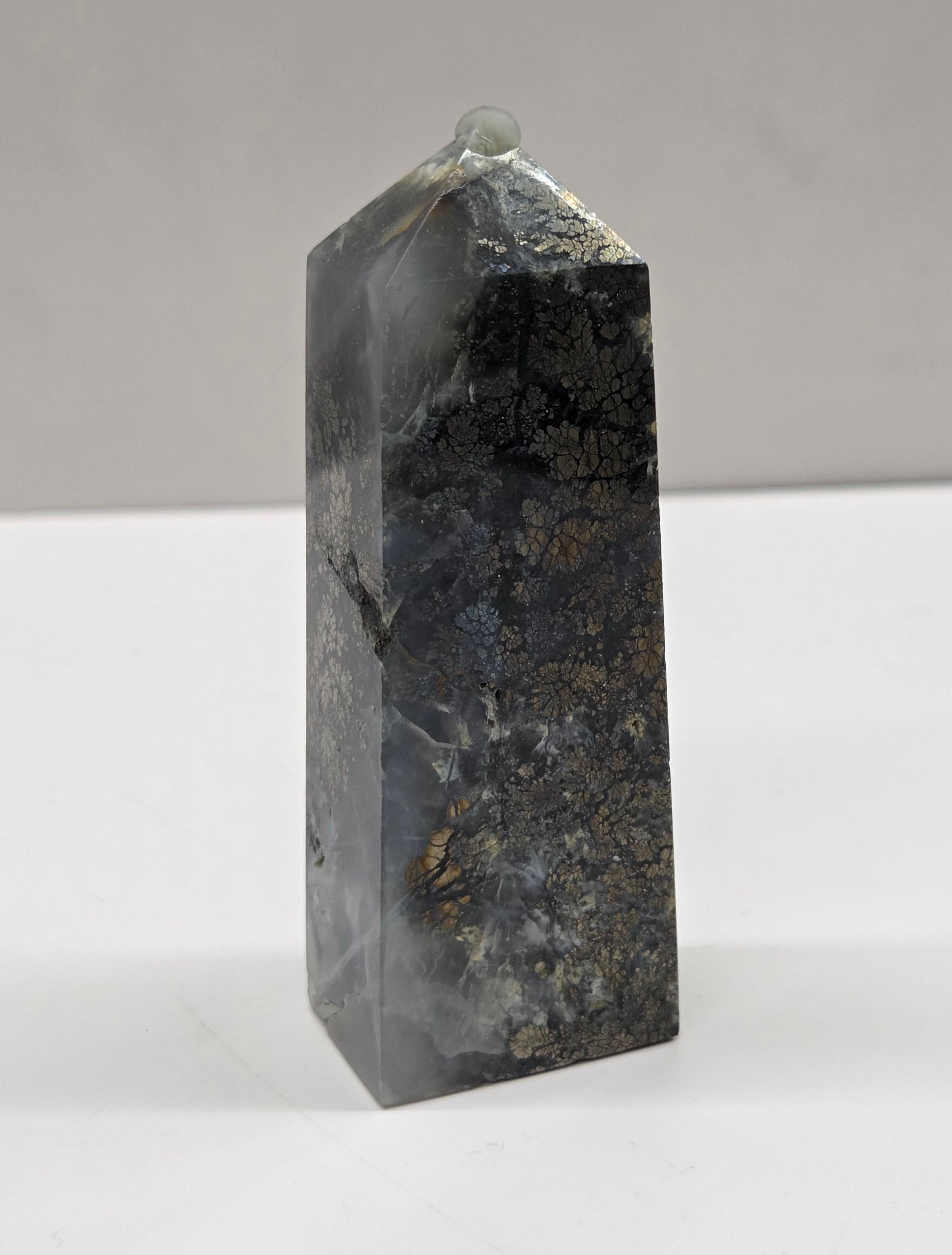 Rectangular crystal on a white surface with a gray background