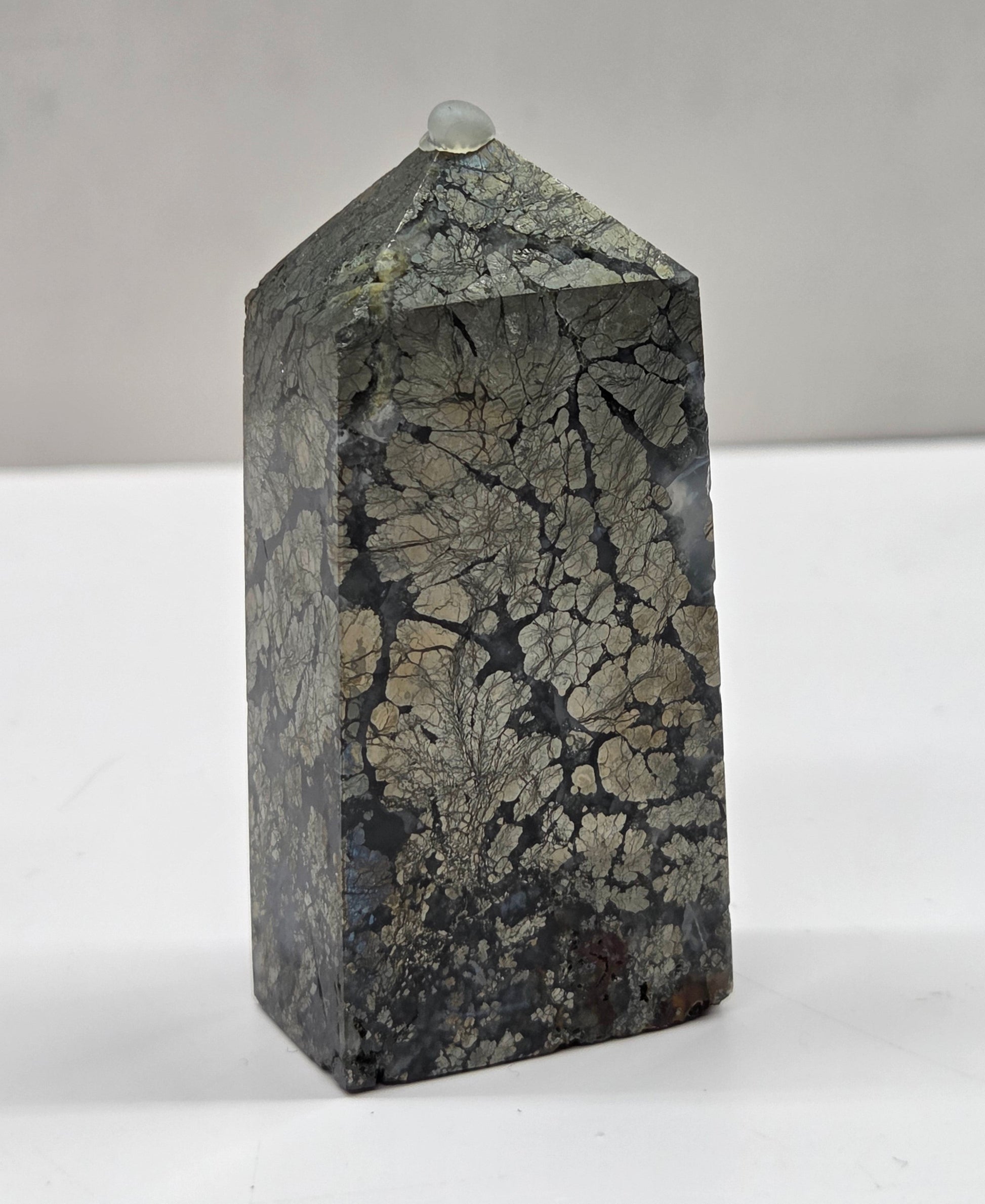 Geometric stone sculpture on a white surface with a gray background