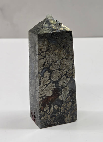 Pyramidal crystal on a white surface with a neutral background