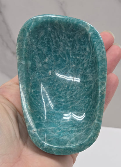 Hand holding a green amazonite carved bowls on a white background