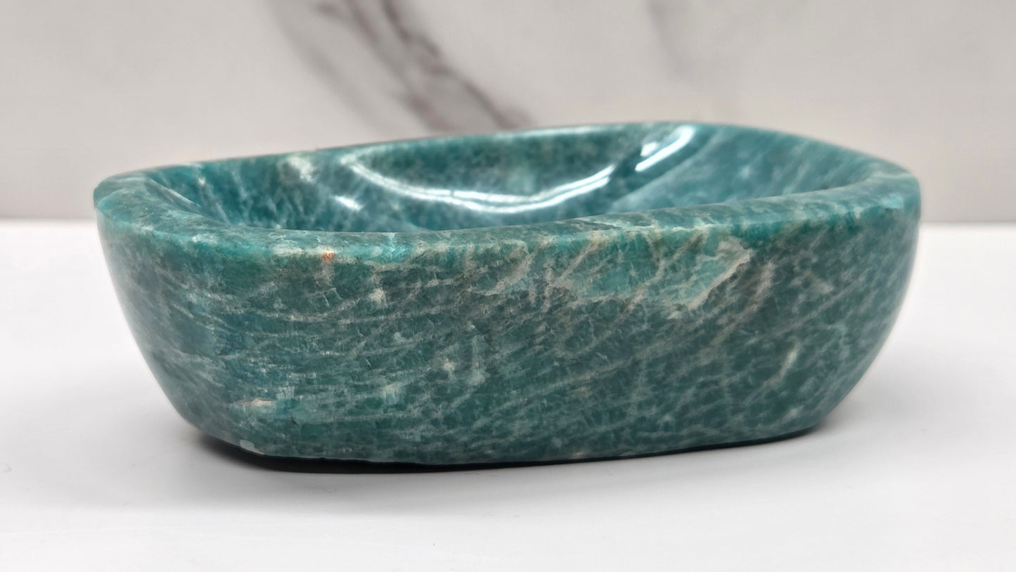 Green amazonite stone bowl on a white surface with a gray background