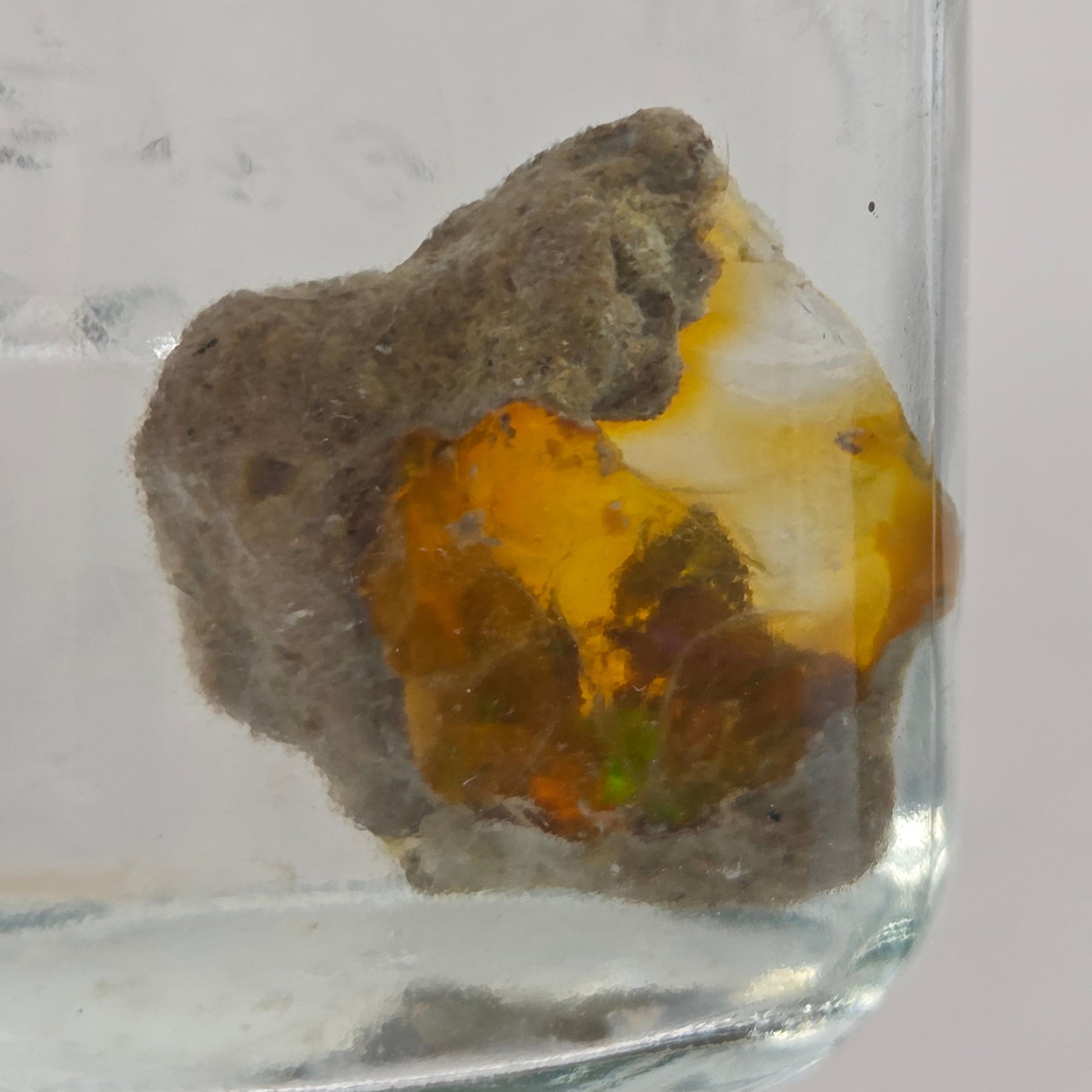 Mineral sample in a clear container on a light gray background