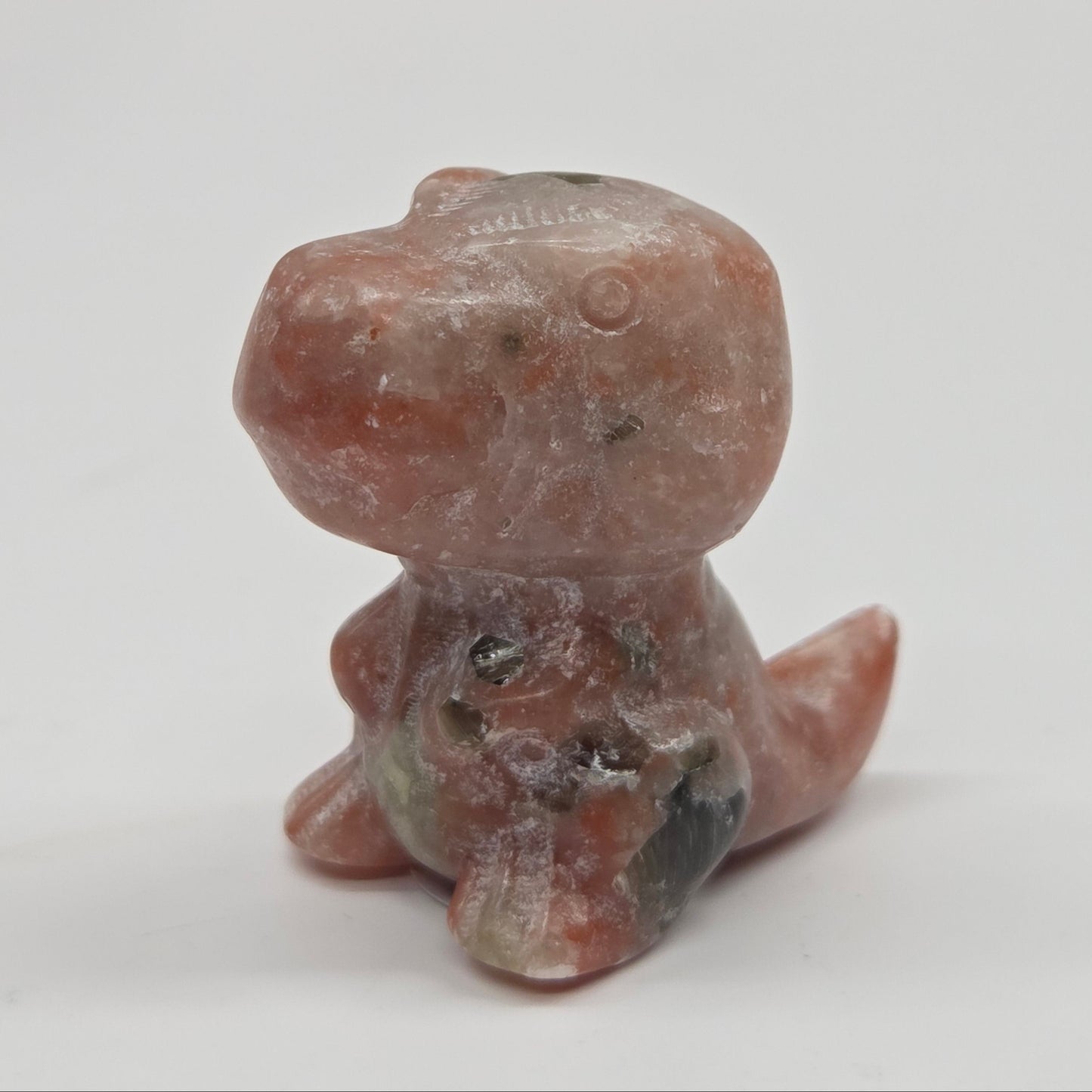 Small stone dinosaur of a creature on a white background