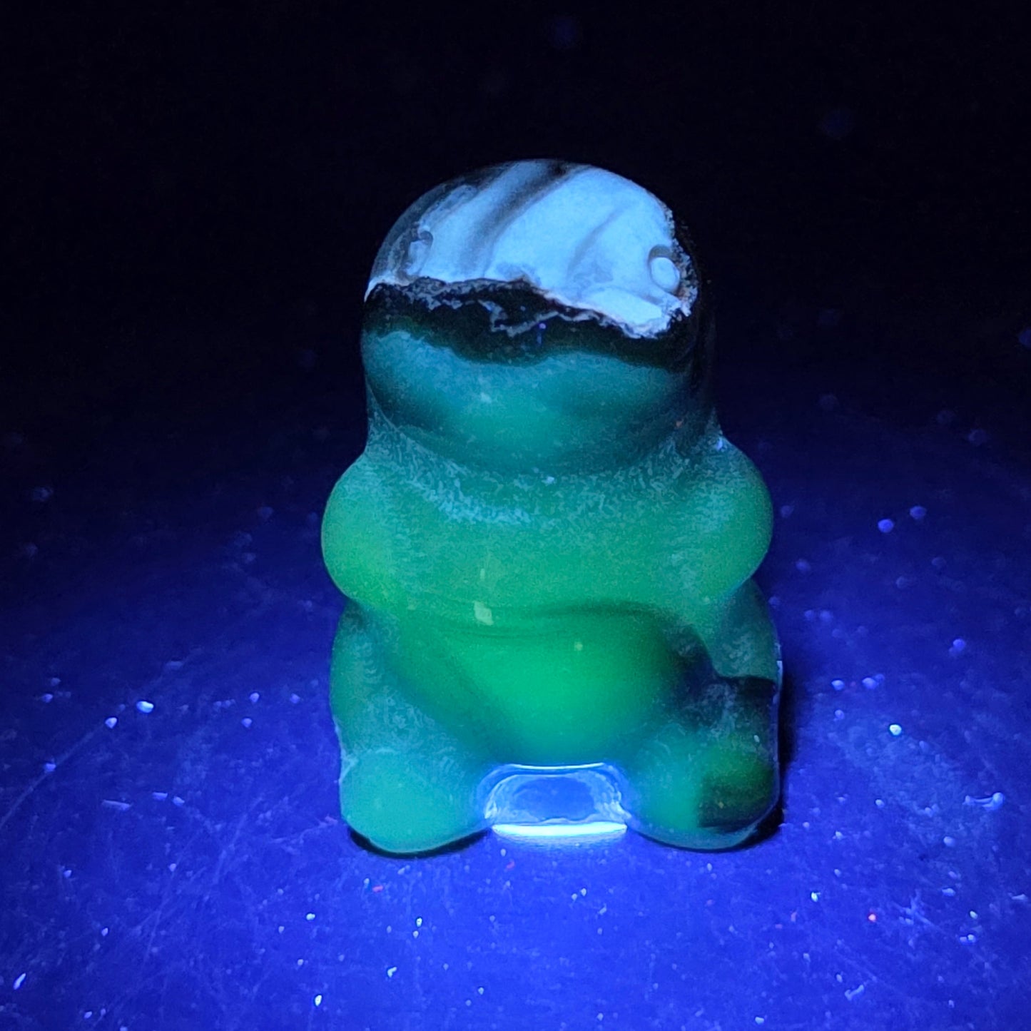 Volcano Agate chubby belly dinosaur on a black background under UV light