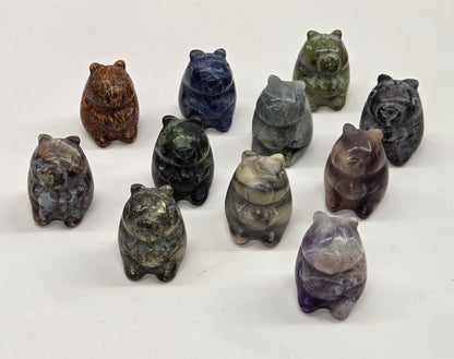 Collection of stone capybara figurines in various colors on a white surface