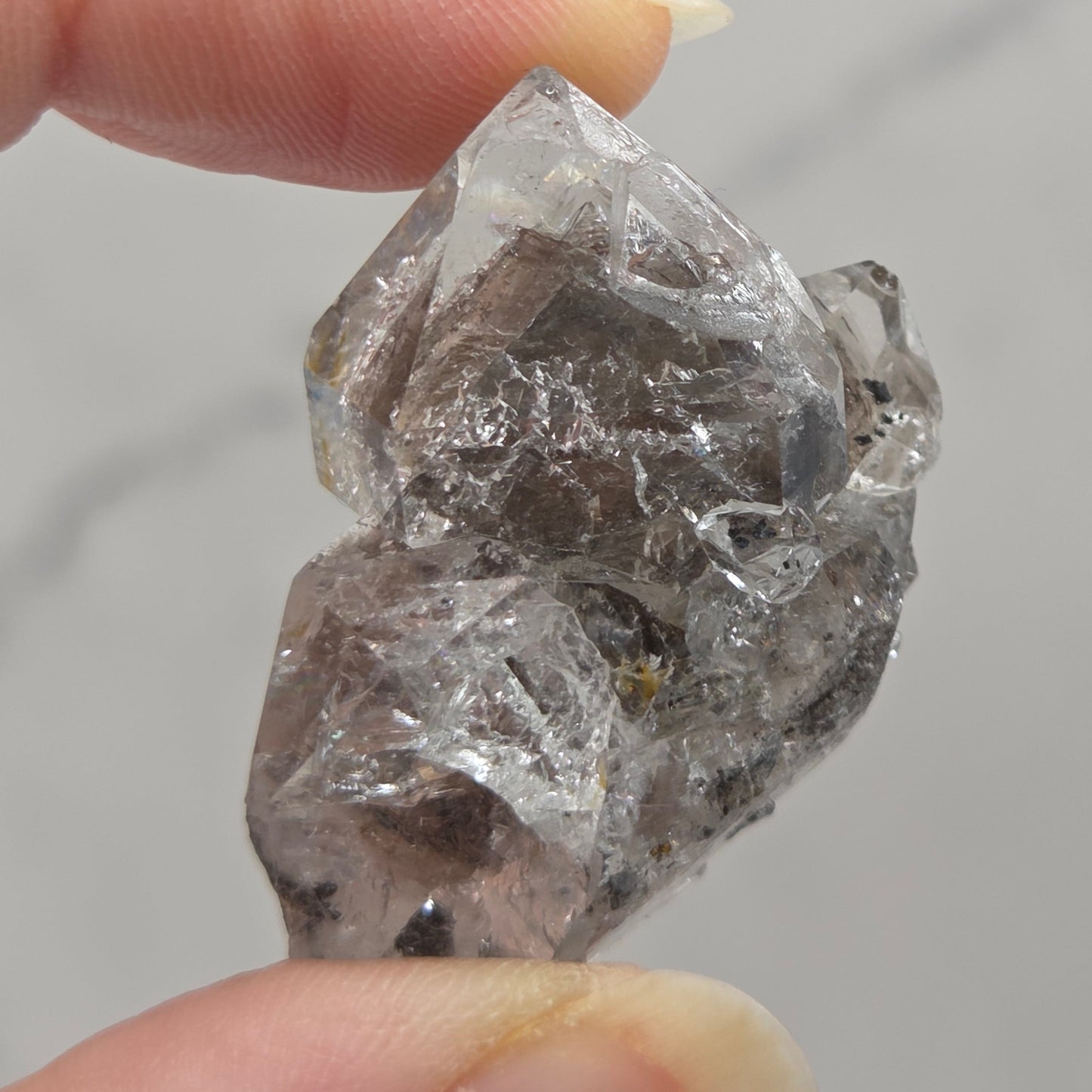 Raw diamond held between two fingers against a neutral background