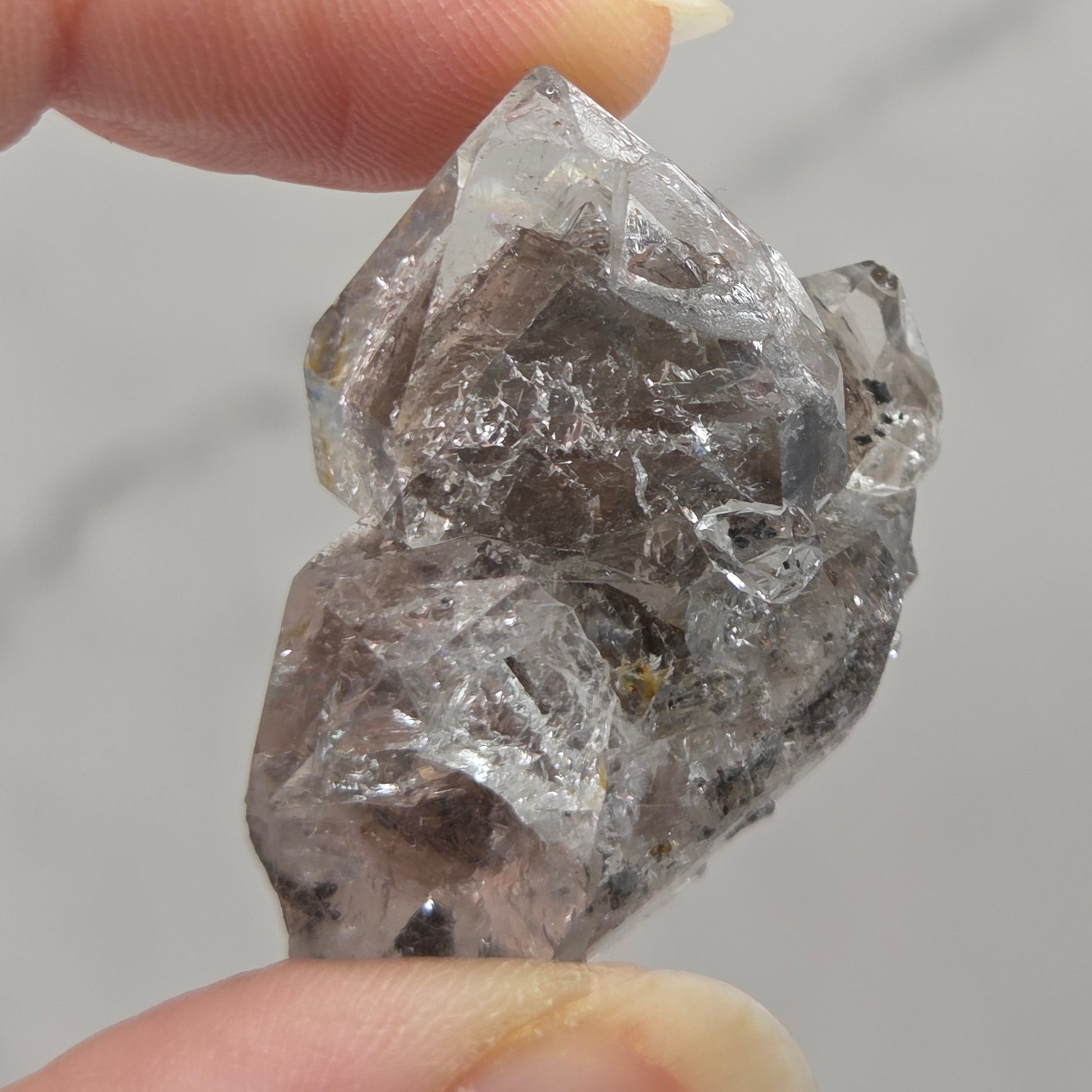 Raw diamond held between two fingers against a neutral background
