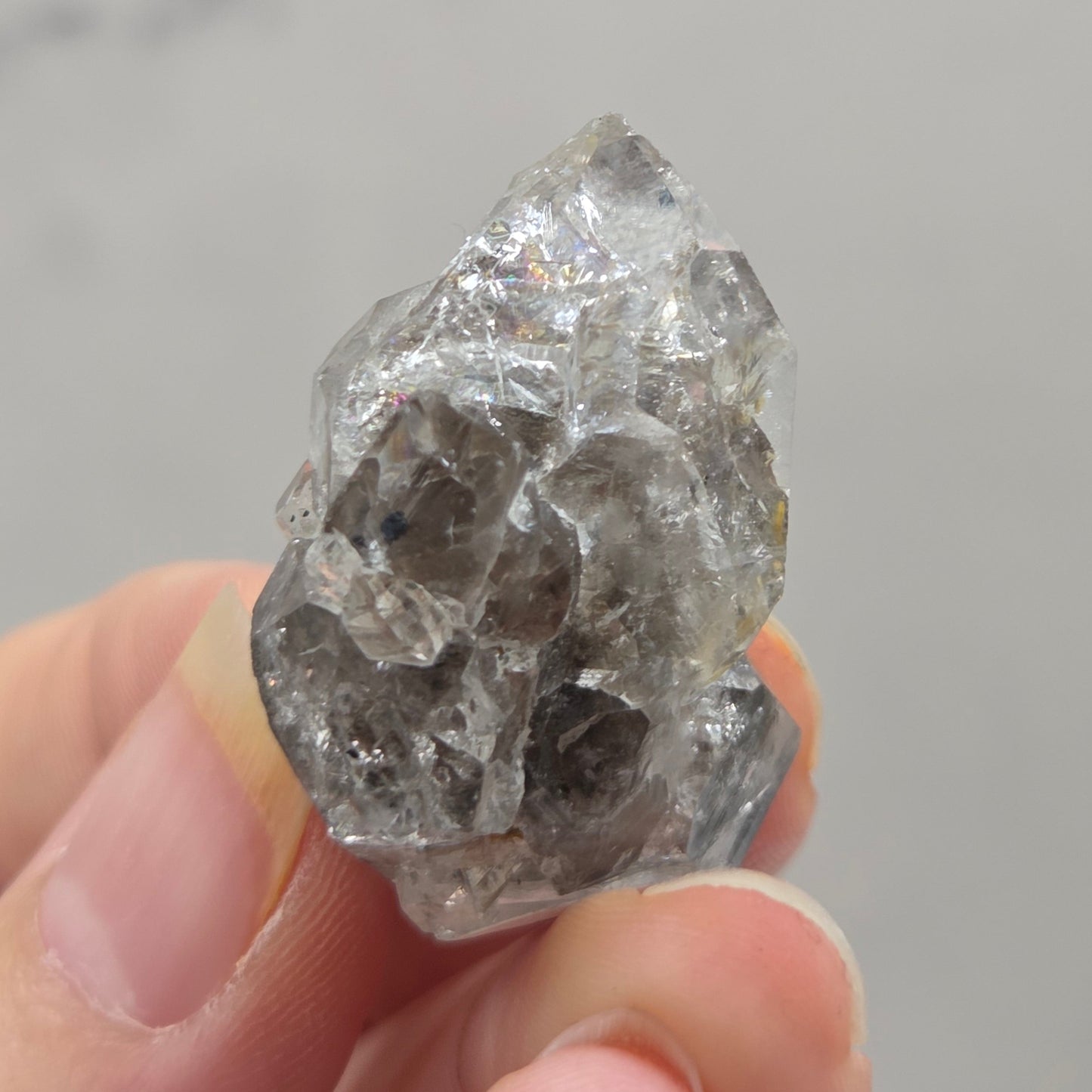 Hand holding a rough diamond crystal against a neutral background