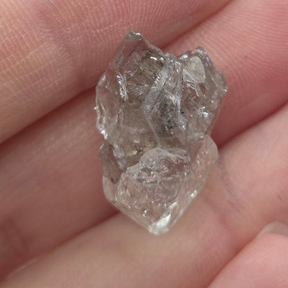 Raw diamond held between fingers against a neutral background
