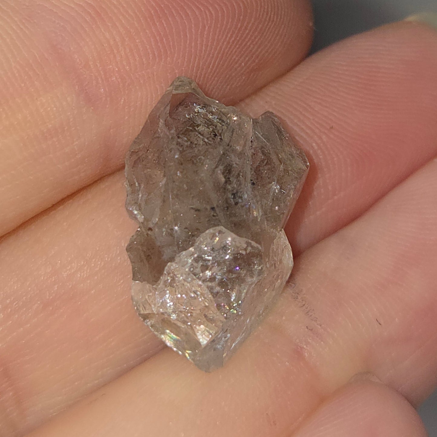 Raw diamond held in a hand against a neutral background