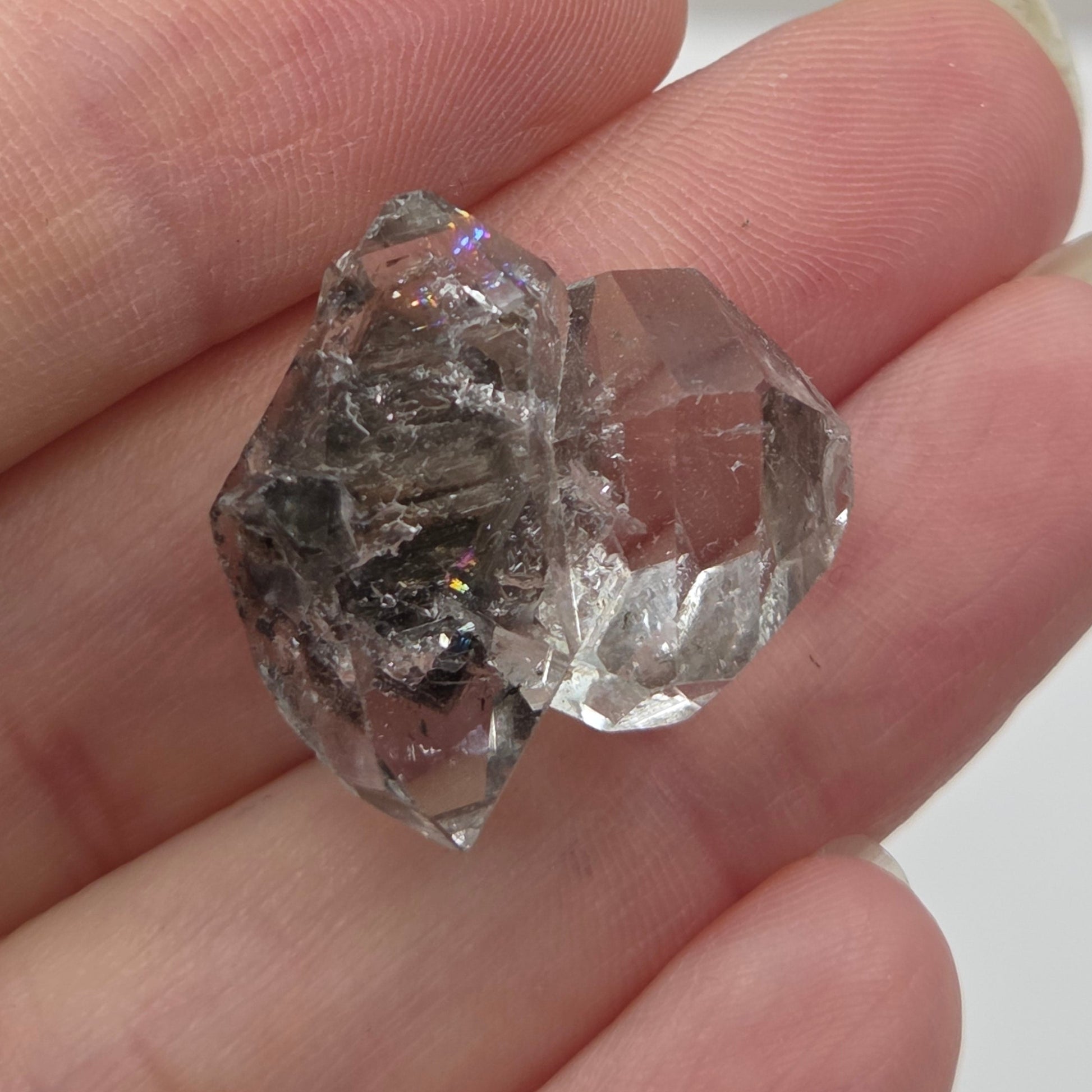 Clear crystal held between fingers against a neutral background