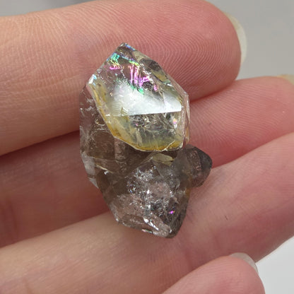 Two rough diamonds held between fingers against a neutral background