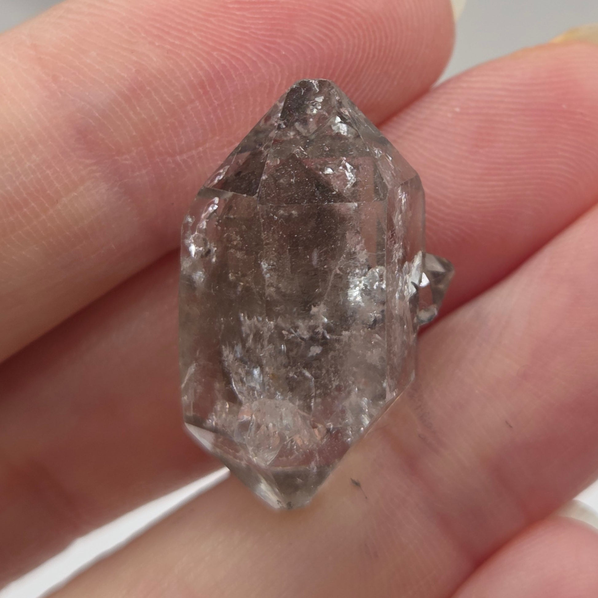 Raw diamond held between fingers against a neutral background