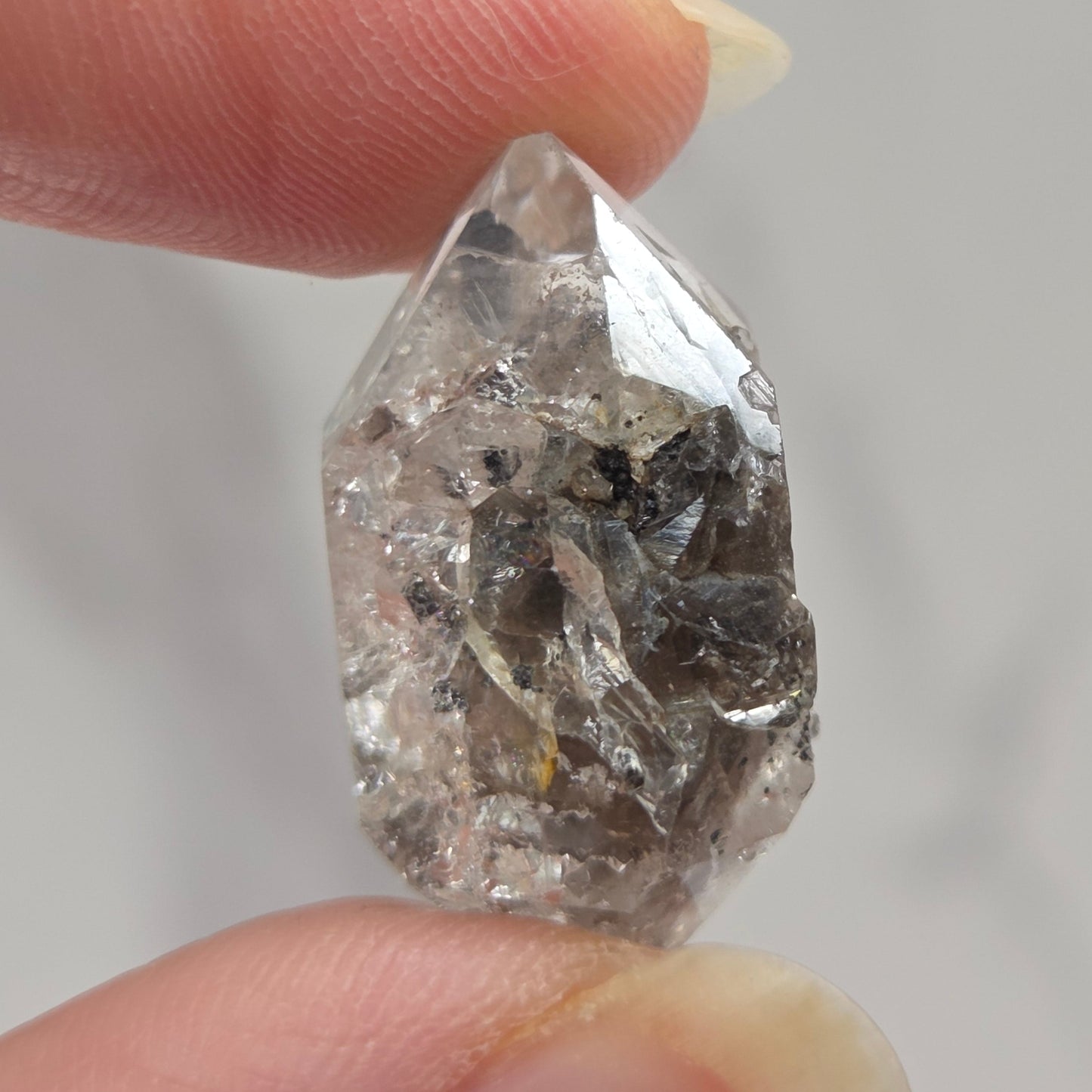 Raw diamond held between two fingers against a neutral background