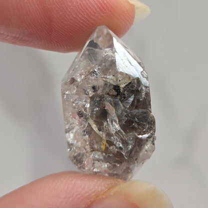 Raw diamond held between two fingers against a neutral background