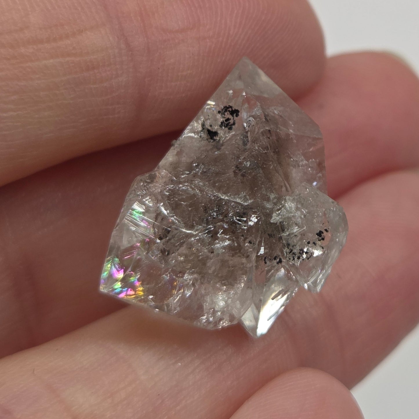 Raw diamond held between fingers against a neutral background