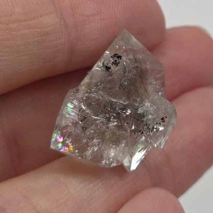 Raw diamond held between fingers against a neutral background