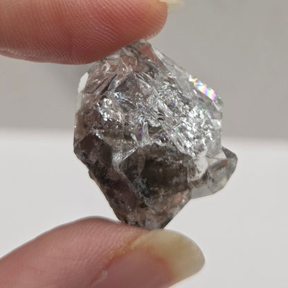 Raw diamond held between two fingers against a neutral background