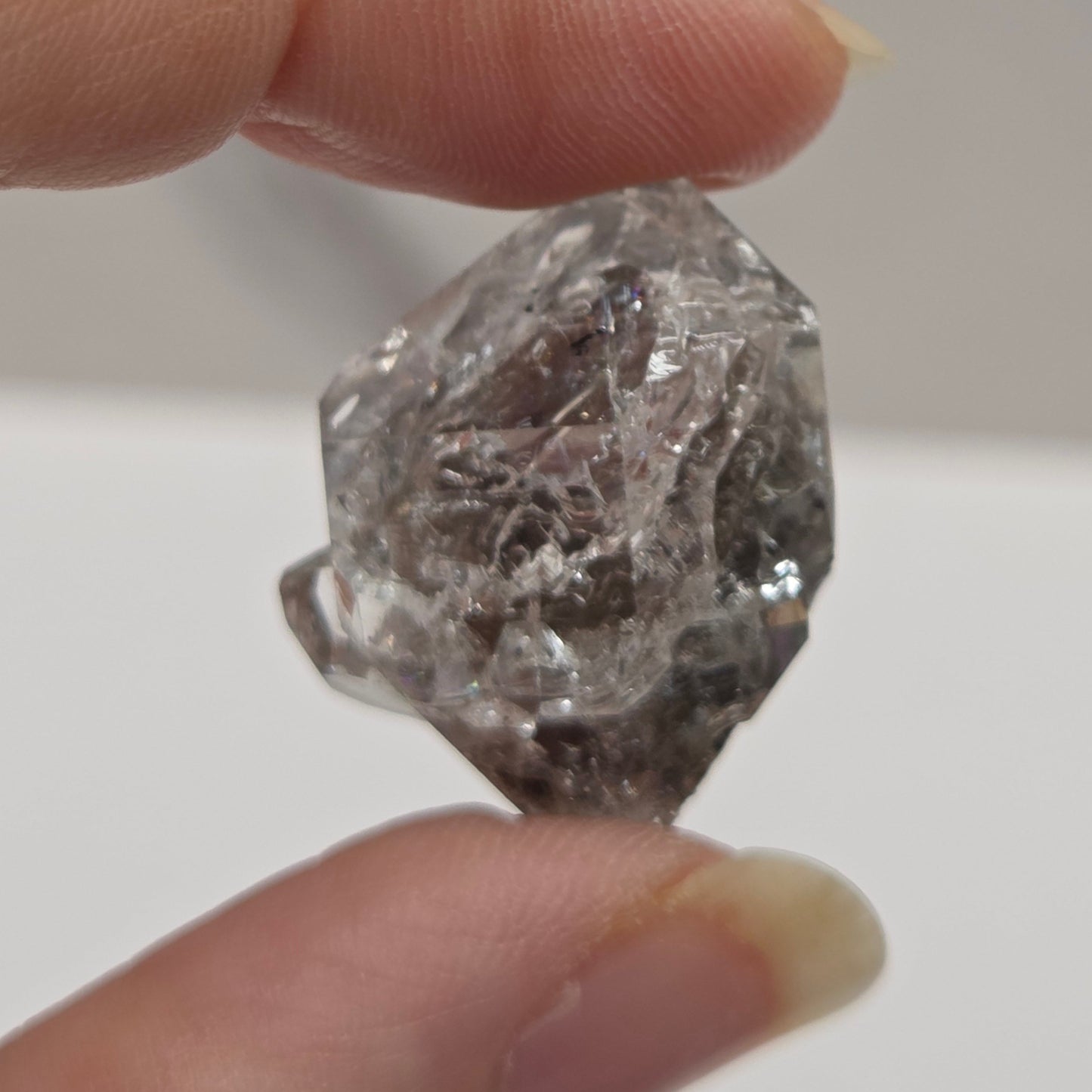Raw diamond held between two fingers against a neutral background