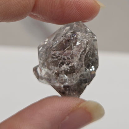 Raw diamond held between two fingers against a neutral background