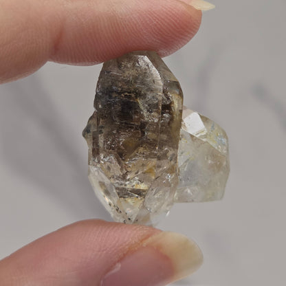 Hand holding a rough diamond crystal against a neutral background