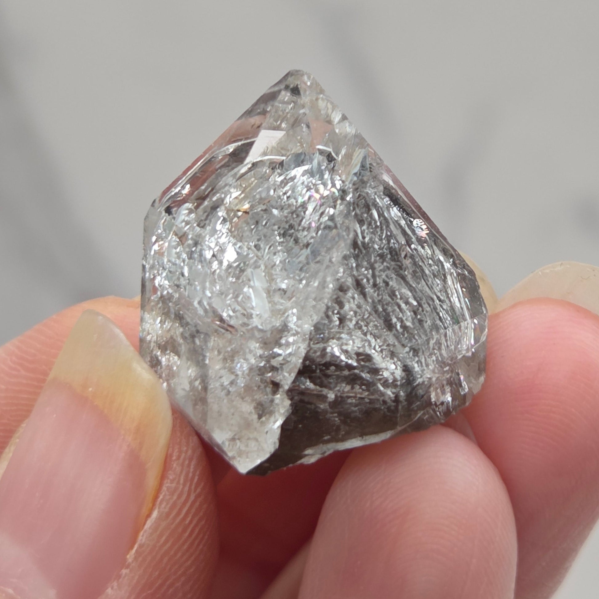 Raw diamond held between fingers against a neutral background