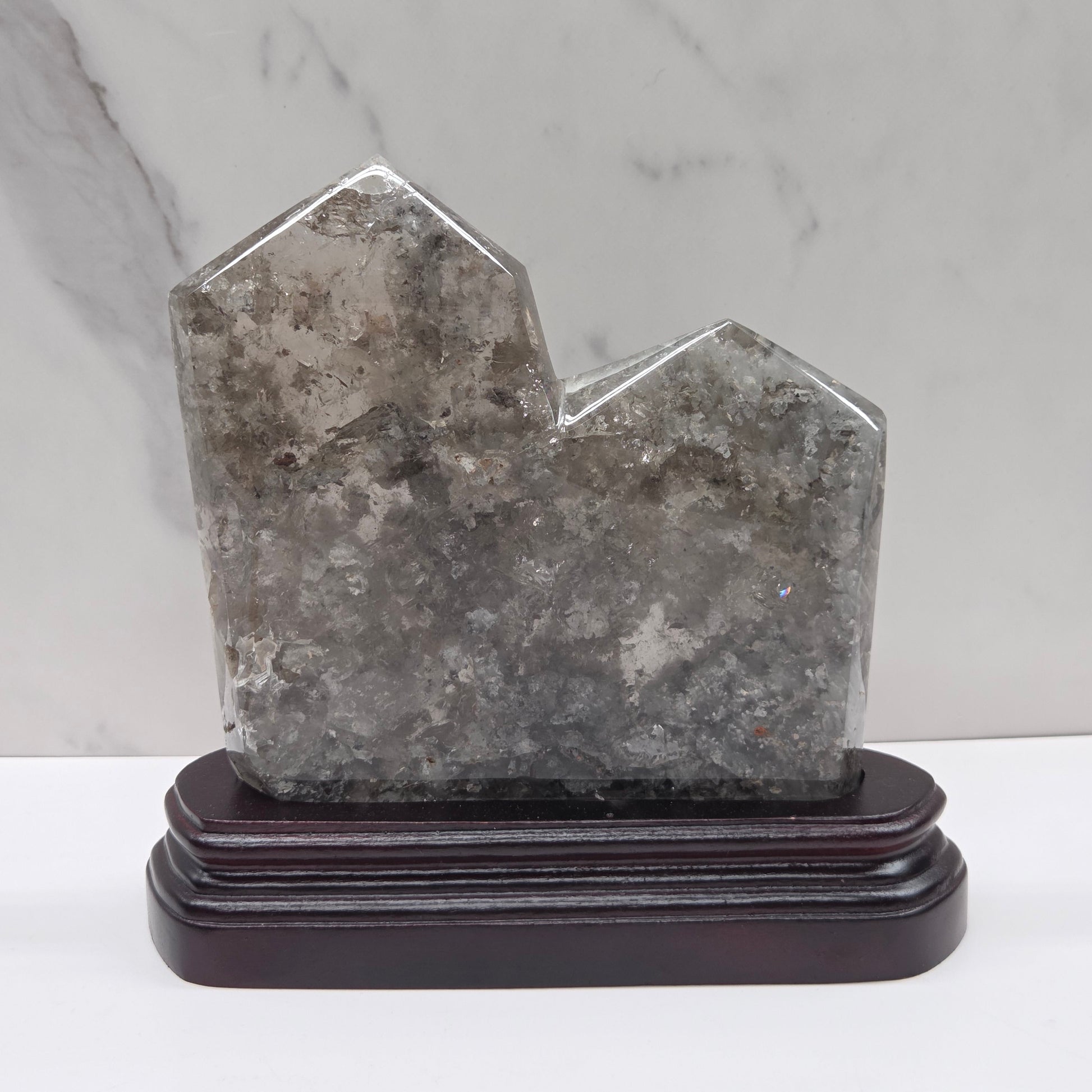 Geometric stone tower on a wooden base against a marble background