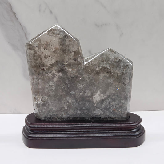 Geometric stone tower on a wooden base against a marble background