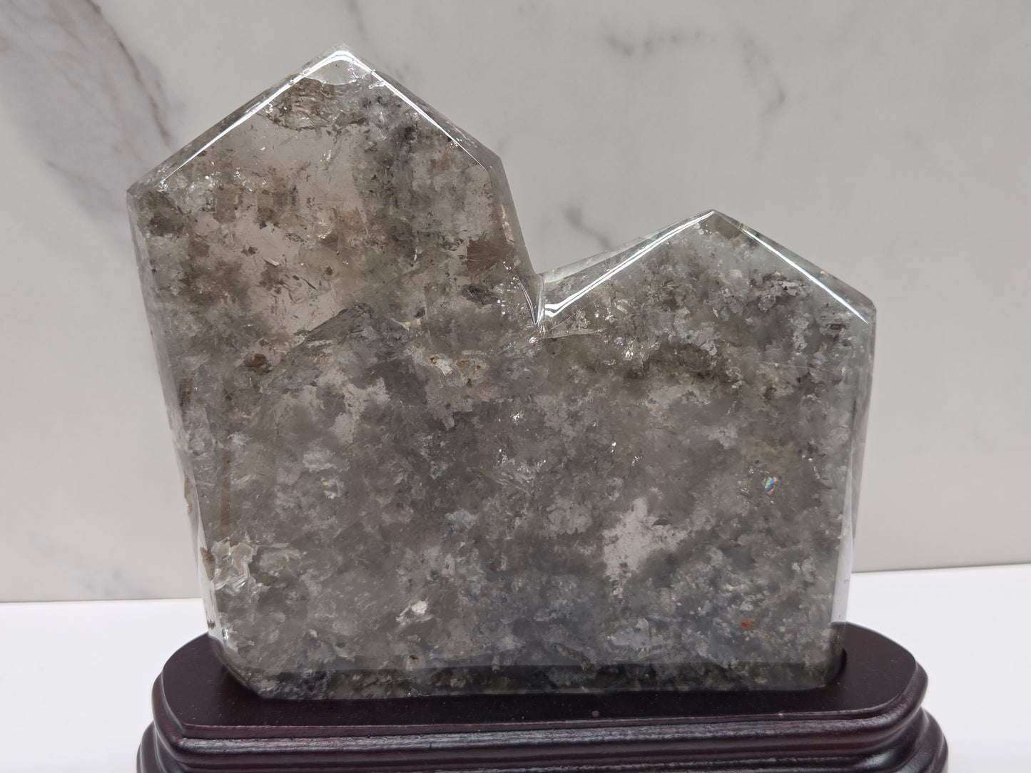 Geometric crystal sculpture on a stand with a marble background