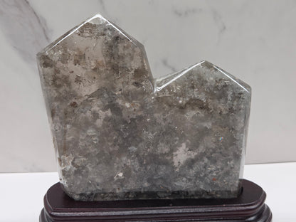 Geometric crystal sculpture on a stand with a marble background