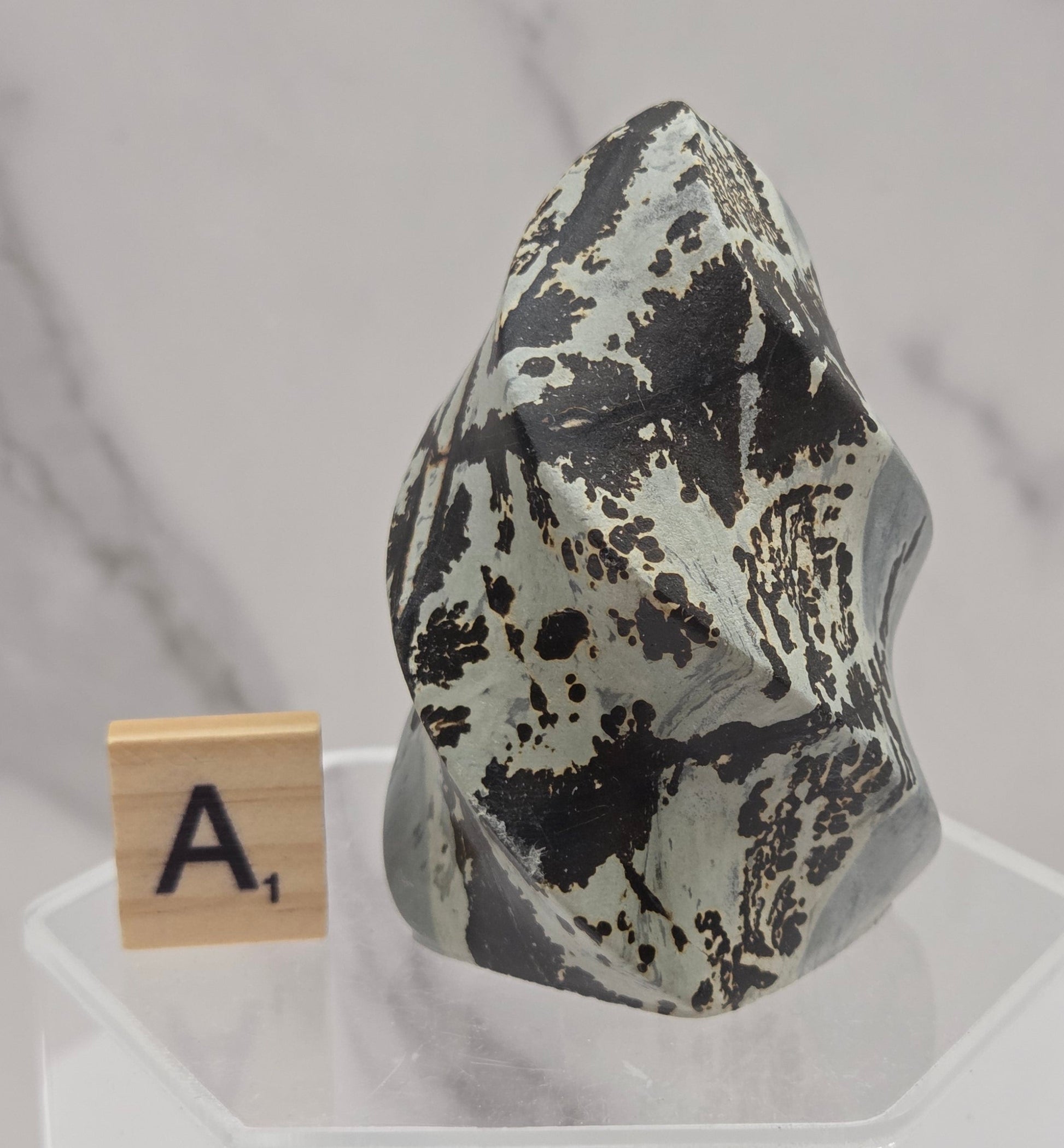 Picture Jasper carving resembling a flame on a clear stand against a neutral background