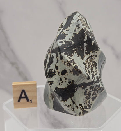 Picture Jasper carving resembling a flame on a clear stand against a neutral background