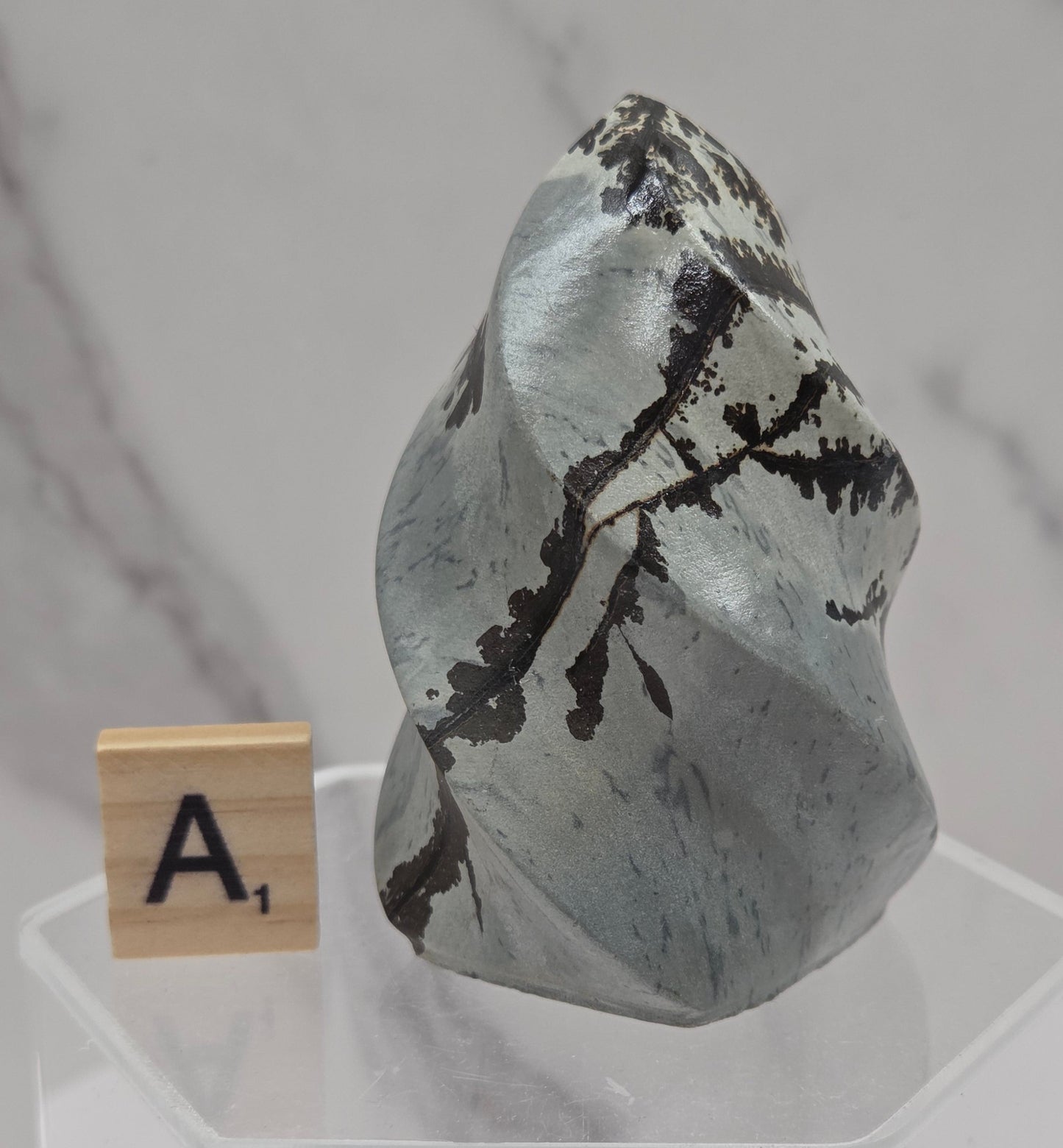 Picture Jasper carving resembling a flame on a clear stand against a neutral background
