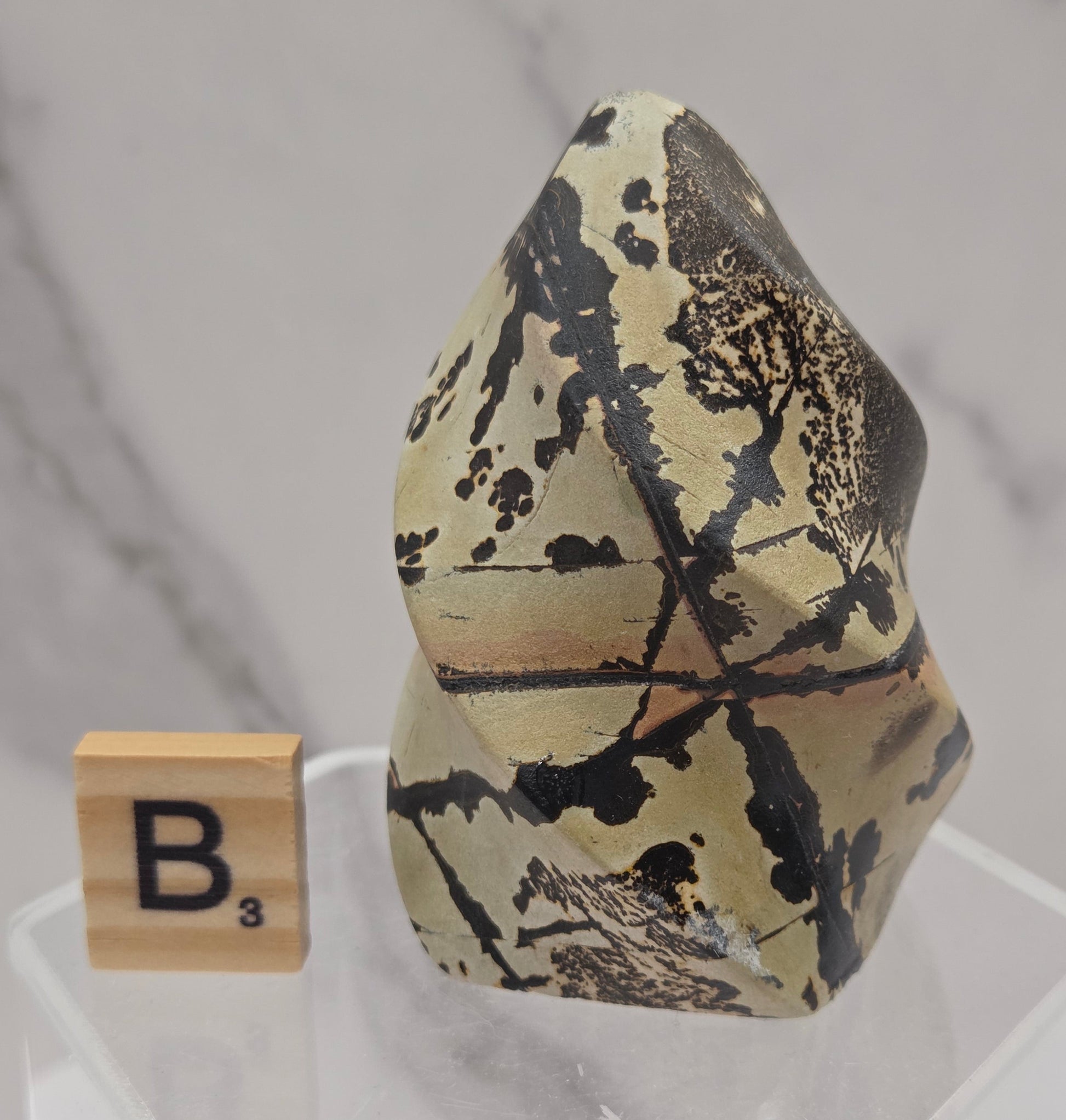 Picture Jasper carving resembling a flame on a clear stand against a neutral background