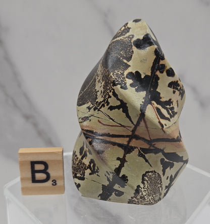 Picture Jasper carving resembling a flame on a clear stand against a neutral background