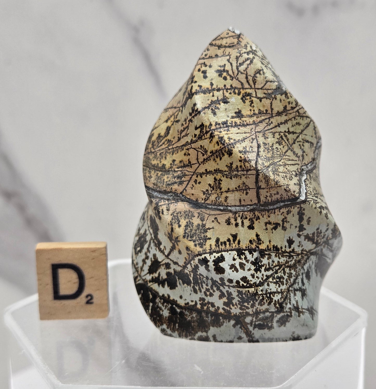 Picture Jasper carving resembling a flame on a clear stand against a neutral background