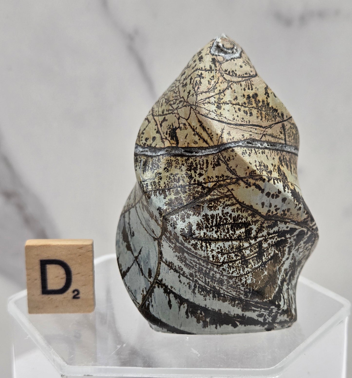 Picture Jasper carving resembling a flame on a clear stand against a neutral background