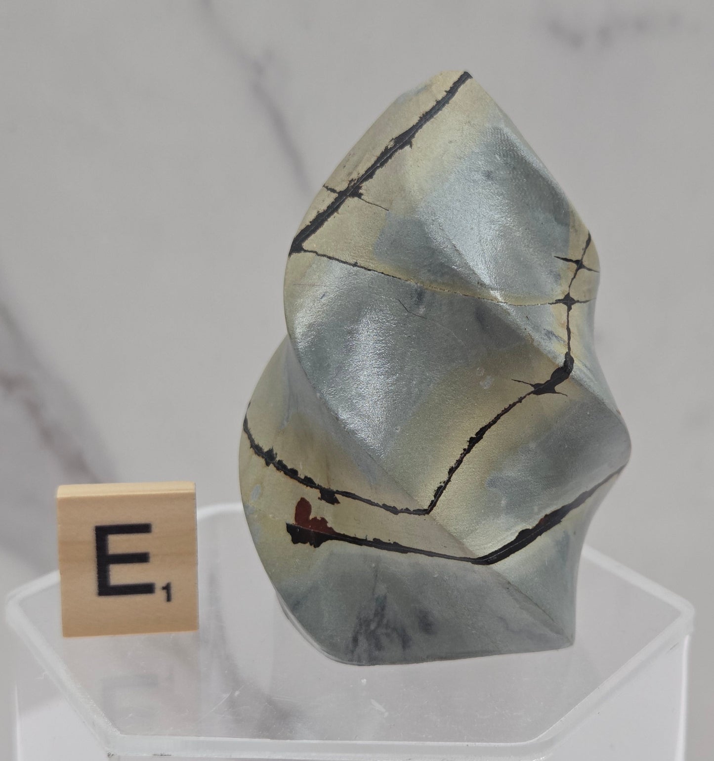 Picture Jasper carving resembling a flame on a clear stand against a neutral background