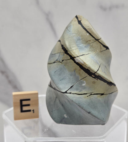 Picture Jasper carving resembling a flame on a clear stand against a neutral background
