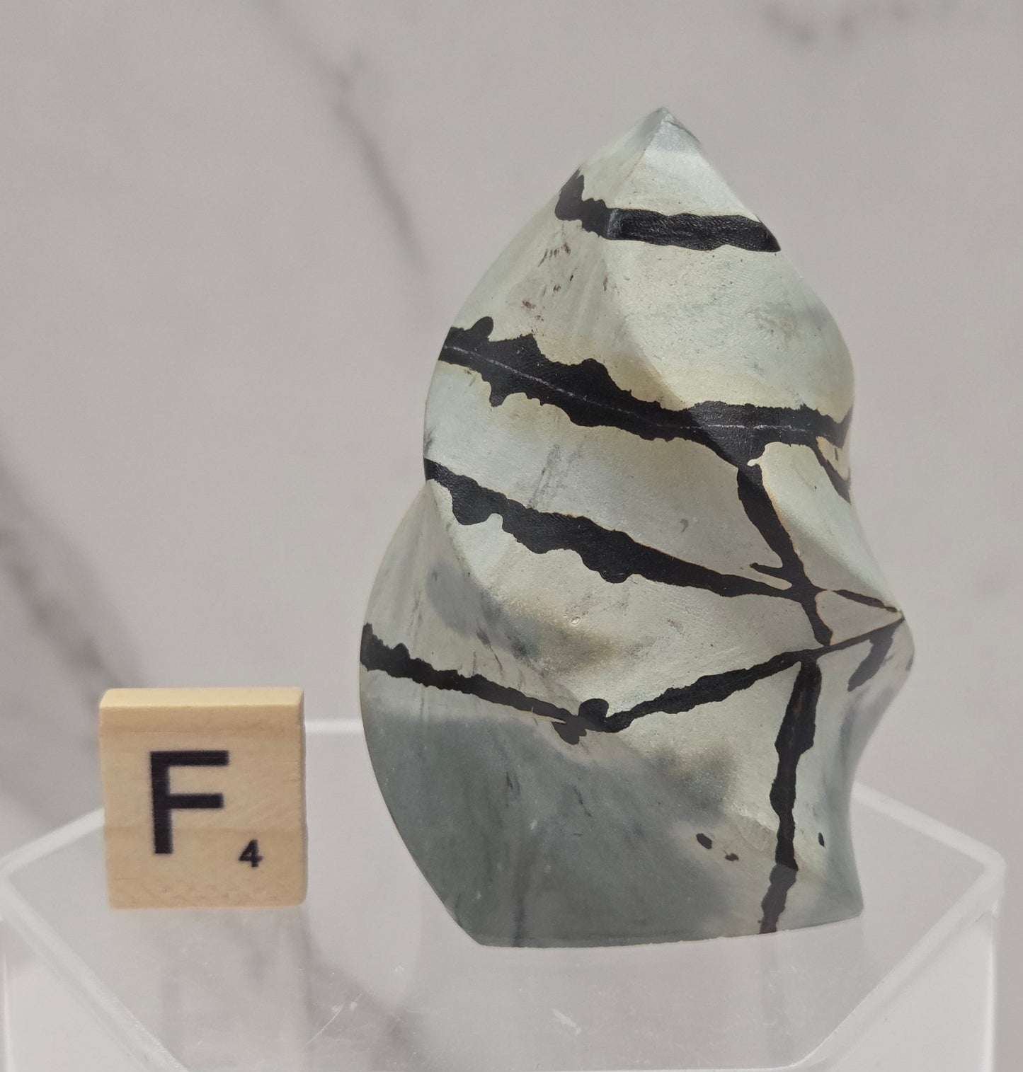 Picture Jasper carving resembling a flame on a clear stand against a neutral background
