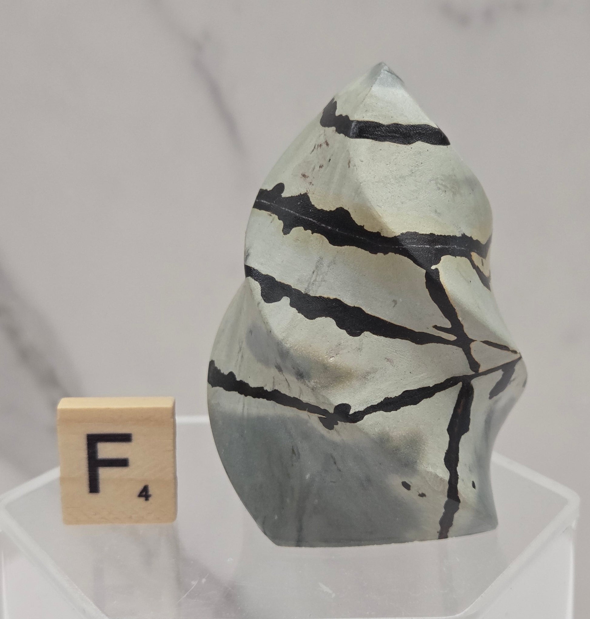 Picture Jasper carving resembling a flame on a clear stand against a neutral background
