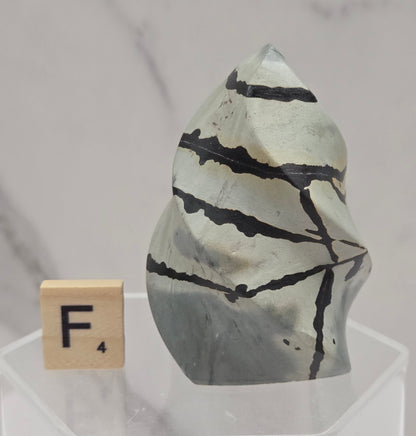Picture Jasper carving resembling a flame on a clear stand against a neutral background