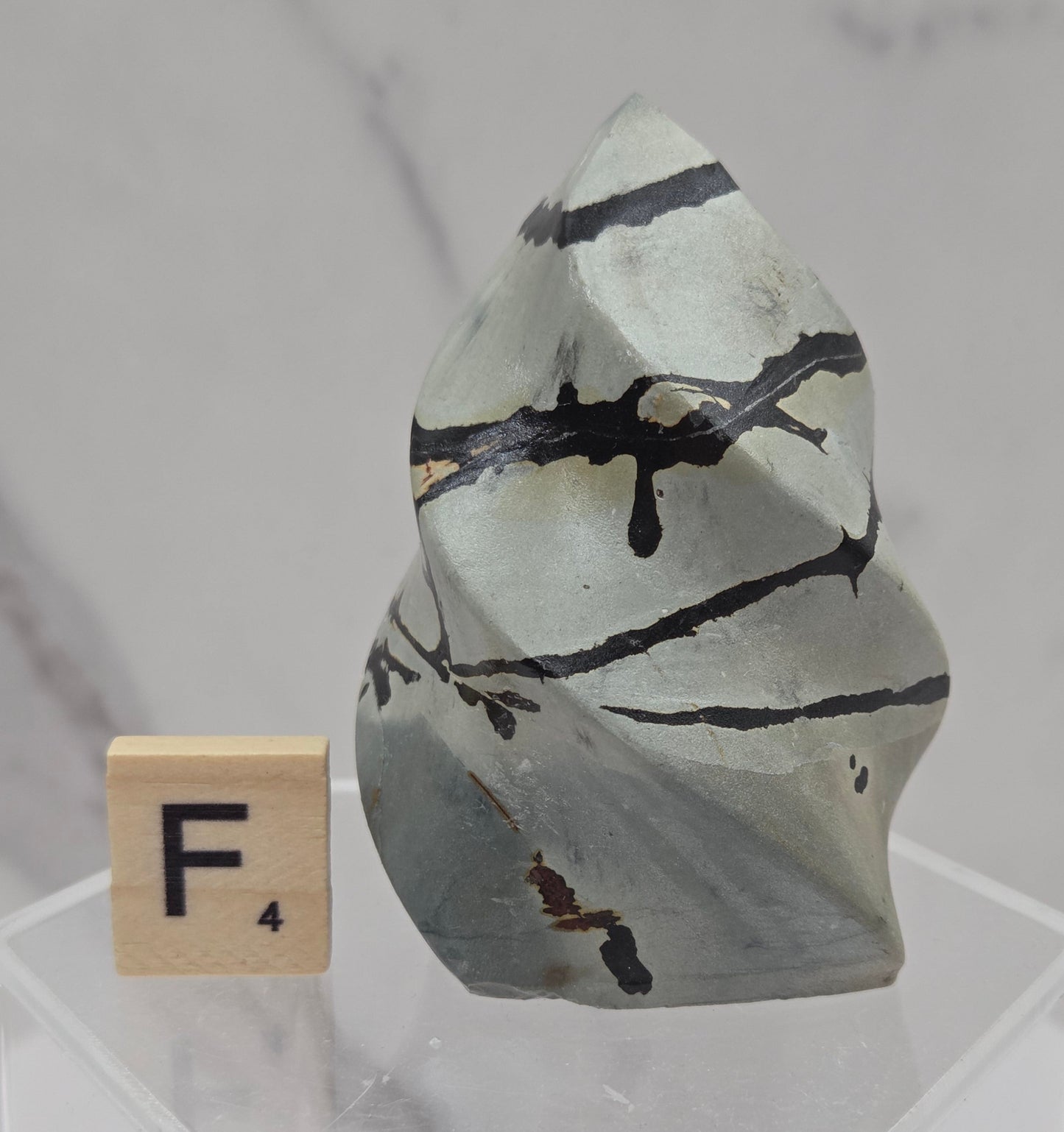 Picture Jasper carving resembling a flame on a clear stand against a neutral background