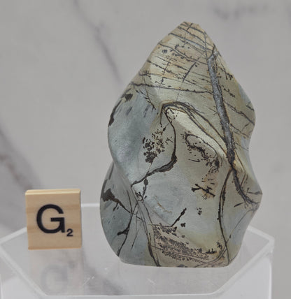 Picture Jasper carving resembling a flame on a clear stand against a neutral background