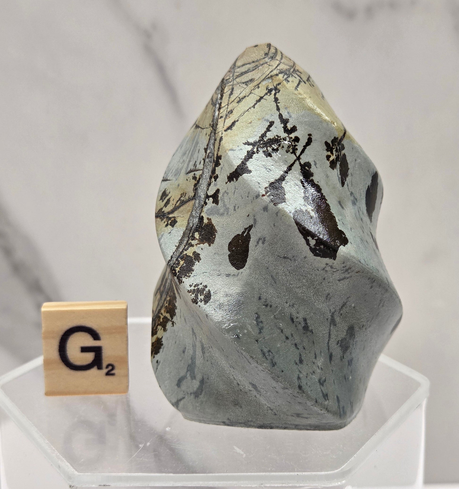 Picture Jasper carving resembling a flame on a clear stand against a neutral background