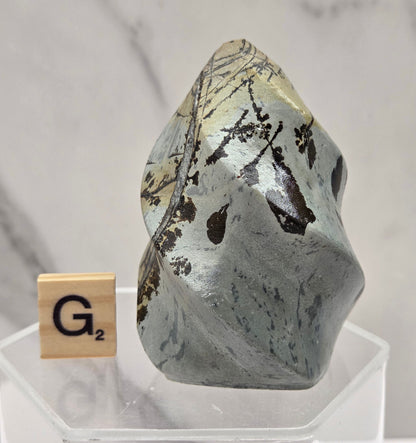 Picture Jasper carving resembling a flame on a clear stand against a neutral background