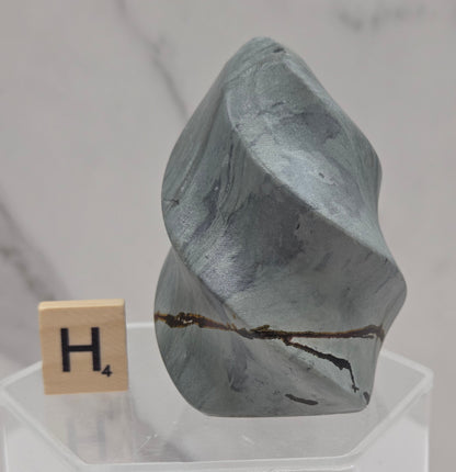 Picture Jasper carving resembling a flame on a clear stand against a neutral background