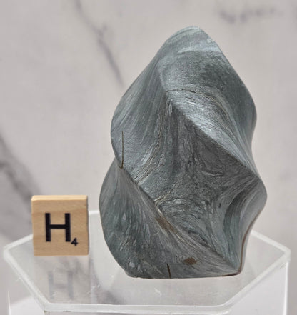 Picture Jasper carving resembling a flame on a clear stand against a neutral background